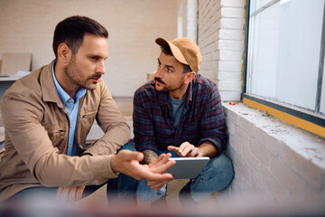 Construction worker using digital tablet with home owner during renovating process.