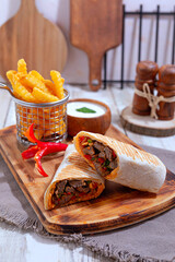 Closeup of pouring chocolate syrup onto a slice of homemade walnut fruitcake in white ceramic dish with a cup of coffee and red ripe apple in