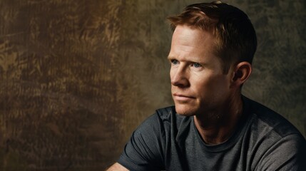Obraz premium Introspective Man in a Gray Shirt Against a Textured Background