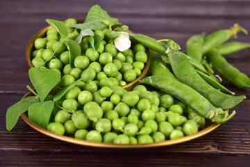 Young green peas in a bowl on a dark background.Close-up.
