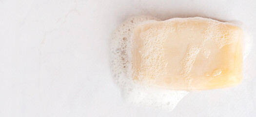 Top view of organic scented antibacterial wet square soap bar with foam and bubbles on grey background with copy space used in shower for healthy body hygiene and as skin care treatment cosmetics