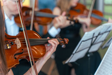 Professional symphony orchestra performing on stage and playing classical music concert, violinist playing in the foreground, art and entertainment concept