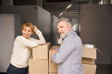 Adult couple standing near loaded trolley in storehouse