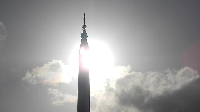 Ancient Egyptian obelisk Flaminio in Rome in Italy, sky with sun and moving clouds Iridescence, Irisation. Topics: weather, optical phenomenon, history, art, tourism
