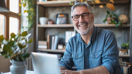 Fototapeta premium Cheerful senior man working on laptop at home office with bright smile. Mature businessman working remote from home with laptop and files.