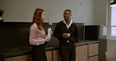 Diverse business workers having a casual conversation in an office break room, promoting a relaxed atmosphere.