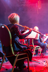 Woman playing the flute. Concert of the symphony orchestra under bright scenic spotlights. © Art Event