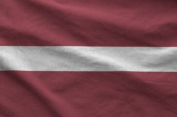 Latvia flag depicted on folded wavy fabric of old cloth close up