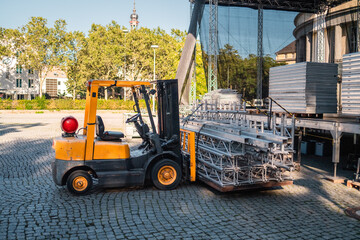 Yellow Heavy Load Forklift Truck Transporting Stage Equipment to the Event
