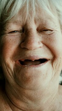 Portrait of a cheerful old woman looking at the camera. Close-up of the face and eyes of a toothless old woman. vertical video