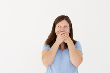 Portrait of a shocked young girl in blue t-shirt looking aside with mouth covered isolated over white background