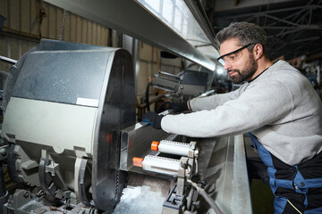 Middle-aged male cuts an aluminum profile using modern equipment