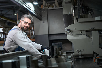 Smiling man working with aluminum profile in production workshop