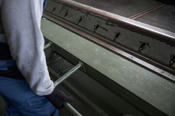 Worker forms a bend of aluminum profile on special machine