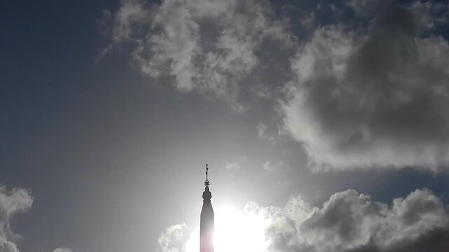 Ancient Egyptian obelisk Flaminio in Rome in Italy, sky with sun, flying birds and moving clouds Iridescence, Irisation. Topics: weather, optical phenomenon, history, art, tourism