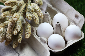 Chicken eggs in a cardboard box and dry flowers