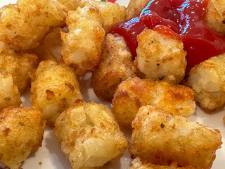 Closeup of cooked potato tots and ketchup on a plate ready to eat