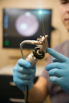 Doctor inspecting medical instrument before anoscopy procedure