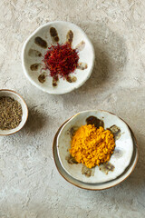 ceramic bowls with oriental spices: cumin, saffron and turmeric powder on the table