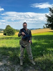 A soldier aiming a rifle.  A soldier with a rifle in his hand standing in the forest.  Dressed in camouflage.