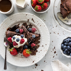 Homemade chocolate crepes topped with whip cream, berries and chocolate shavings