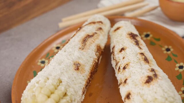 Slow motion of two elotes prepared with mayonnaise, Cheese and red sauce, Mexican food