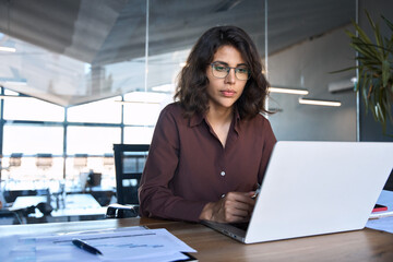 Busy 30s latin hispanic middle age business woman working on laptop computer in office. Focused...