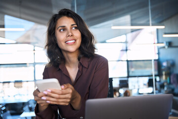 Closeup portrait of young dreaming Indian business woman manager ceo using cell phone mobile app....