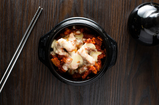 Cheese buldak chicken with chopsticks served in dish isolated on wooden table top view of korean food