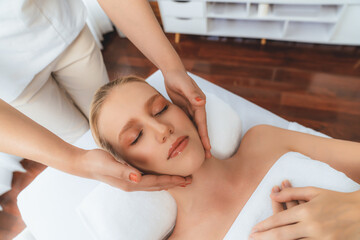 Caucasian woman enjoying relaxing anti-stress head massage and pampering facial beauty skin recreation leisure in dayspa modern light ambient at luxury resort or hotel spa salon. Quiescent