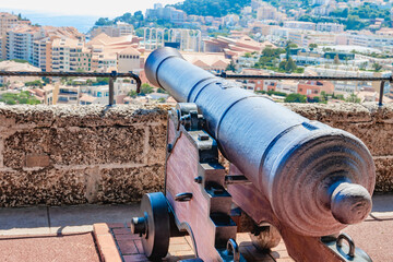 Monaco. Monte Carlo. A historic cannon and pyramid of cannonballs overlooking a coastal city with...
