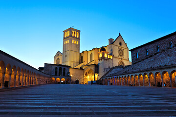 Illuminated Basilica of San Francis of Assisi at sunset under beautiful blue skies, Italy