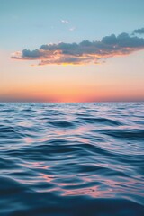 Obraz premium Serene ocean view at sunset with colorful sky, tranquil waves, and a lone cloud - perfect for peaceful and calming scenes.