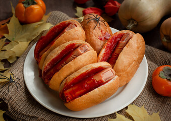 Halloween food. Halloween hot dog. Bloody fingers from sausages in buns with ketchup. Terrible food. Thematic food. Dark wooden background.