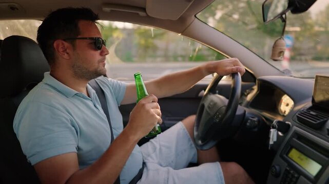 drink and drive. man drinks alcohol while driving a car. Illegal drunk driving. 