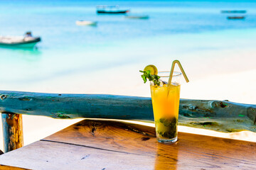 Glass of orange mojito cocktail. Ocean at the background