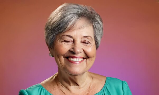 Cheerful senior woman with colored background, gray hair, and cropped hair smiling in studio portrait