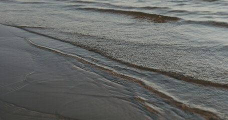 closeup of small waves on a beach at sunset