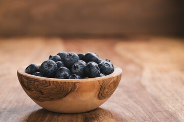 Fresh blueberries in wood bowl on table slightly toned