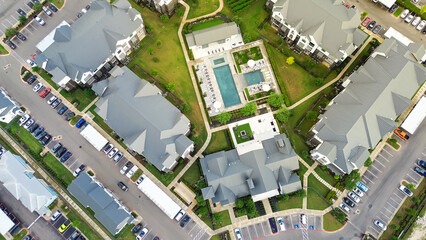 Swimming pool and resort style amenities in modern apartment complex with metal roofing, farmhouses style rental community in Pflugerville, fast-growing city suburbs of North Austin, aerial view