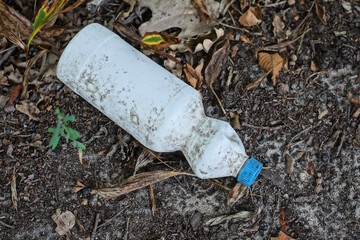 Fototapeta premium garbage from one white plastic bottle lies on the gray earth on the street