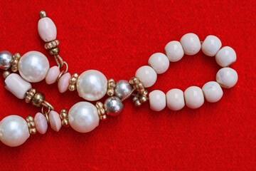 white pearl and bead necklace lie on red table