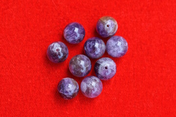 a pile of lilac transparent beads lie on a red table
