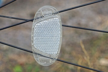 one  white plastic reflector on black metal wheel spokes on the bicycle in the street