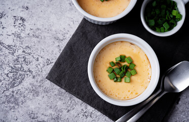 Asian steamed eggs in a bowl with soy sauce and scallions