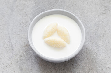 Milk soup with sweet cottage cheese quenelles.  On a plate. Top view