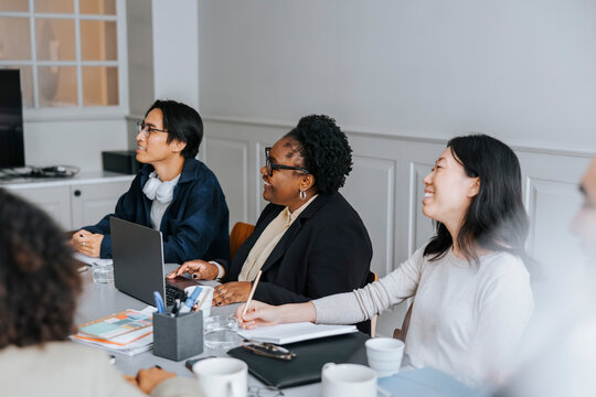 Happy male and female entrepreneurs sitting near table at office