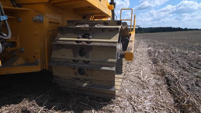 A crawler caterpillar tractor rides across a field