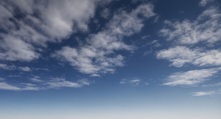 Obraz premium Wolkiger Himmel mit verstreuten, weißen Wolken, die sich vor einem klaren, blauen Hintergrund abheben und eine leichte, sommerliche Atmosphäre schaffen