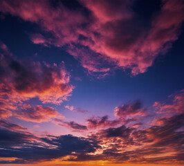 Fototapeta premium Beeindruckender Abendhimmel mit leuchtenden Wolken und intensiven Farbschattierungen, die den Übergang von Tag zu Nacht in einer spektakulären Kulisse zeigen